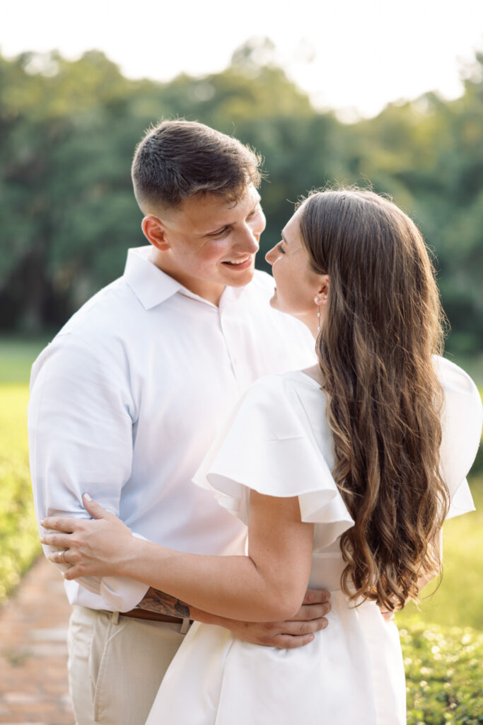 A couple dressed in white looking into each other's eyes at their Afton Villa Gardens engagement session