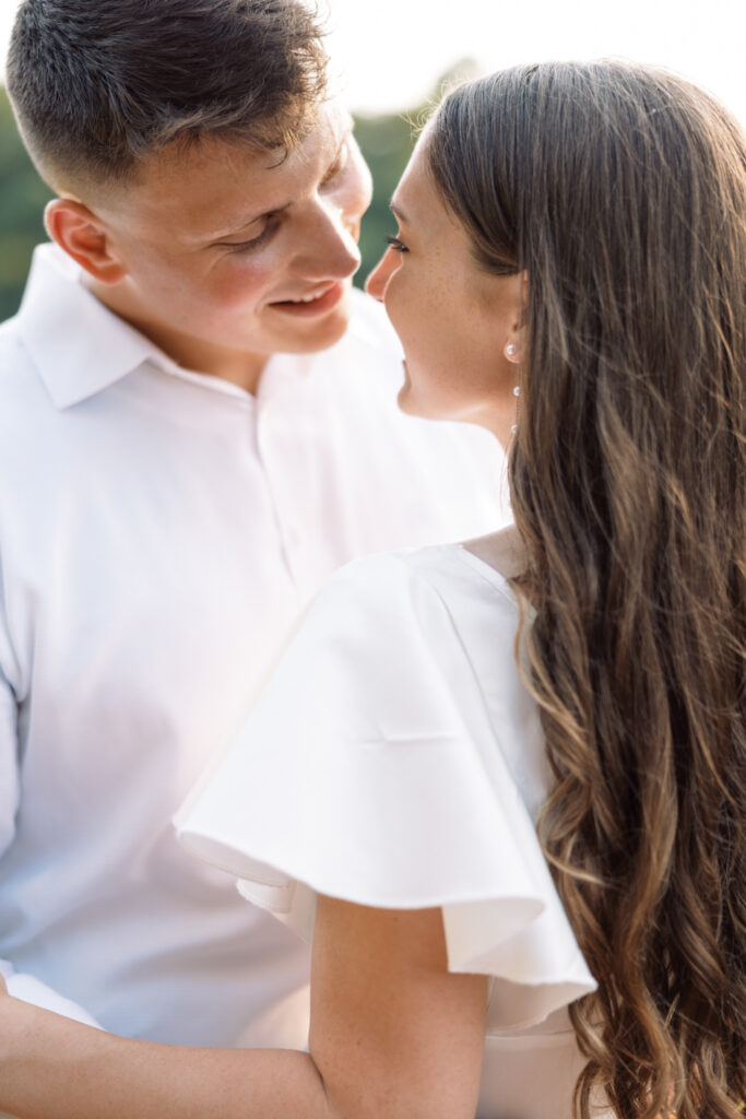 A couple dressed in white looking into each other's eyes at their Afton Villa Gardens engagement session