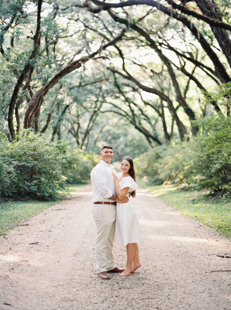 A couple smiling in front of trees at their Afton Villa Gardens engagement session