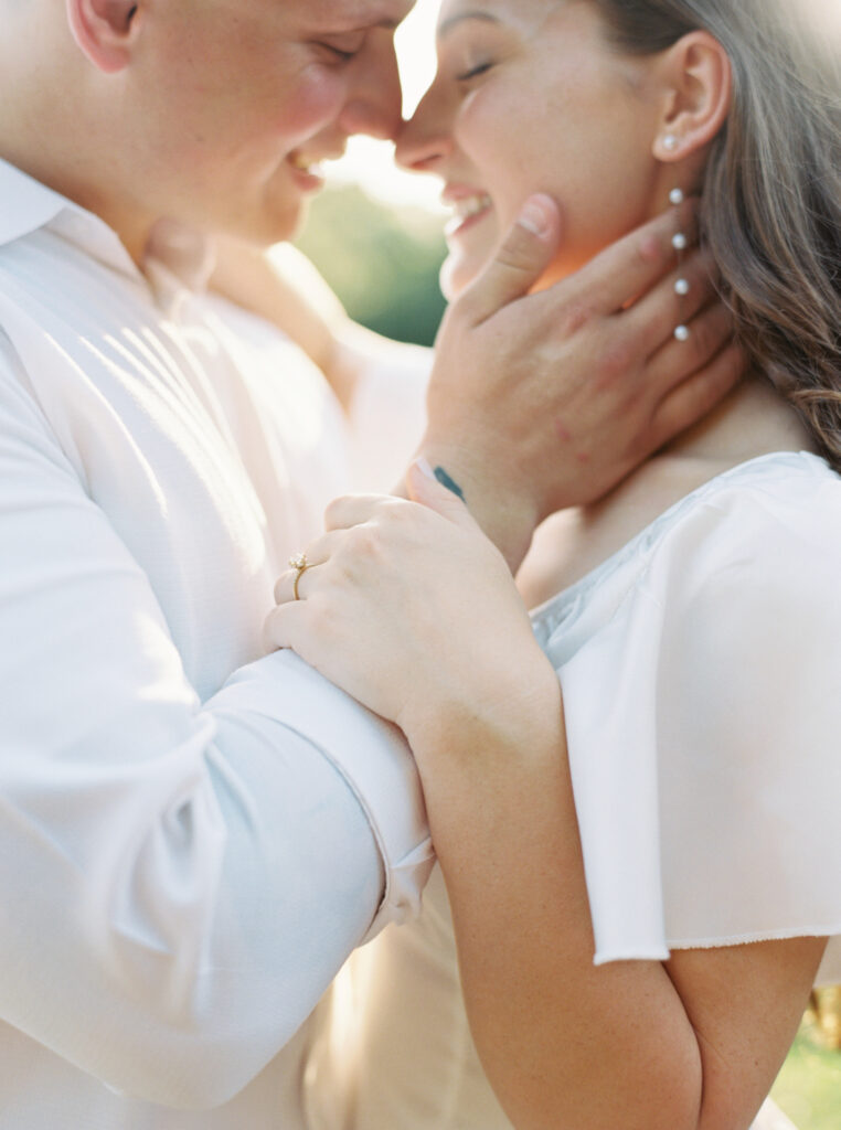 A couple dressed in white posing nose to nose at their Afton Villa Gardens engagement session