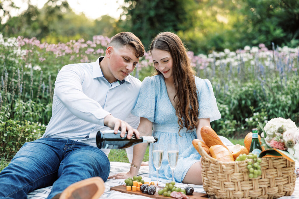 A couple dressed in soft blues having a picnic on the grass at their Afton Villa Gardens engagement session