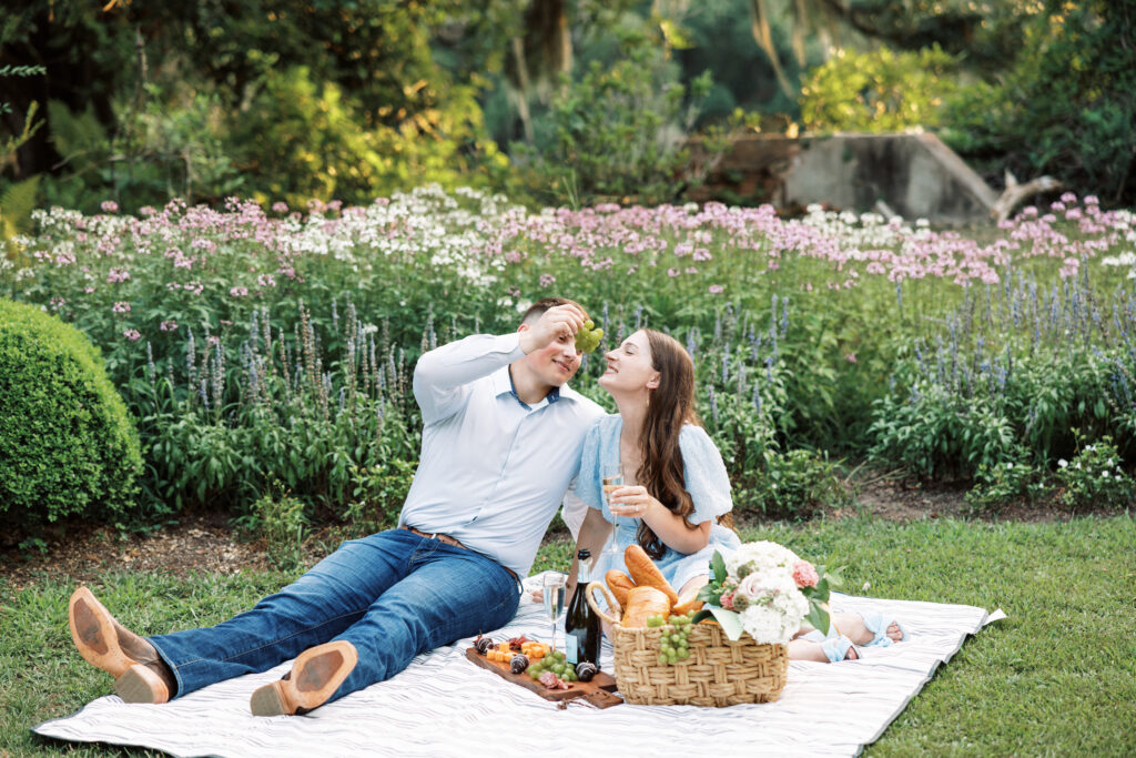 A couple dressed in soft blues having a picnic on the grass at their Afton Villa Gardens engagement session