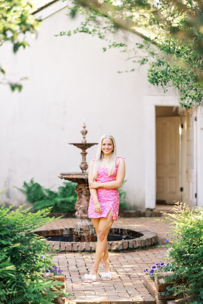 Amy standing in front of a water fountain and cottage hhouse Rosedown Plantation during her senior session at Rosedown Plantation, photographed by Morgan Alysse Photography