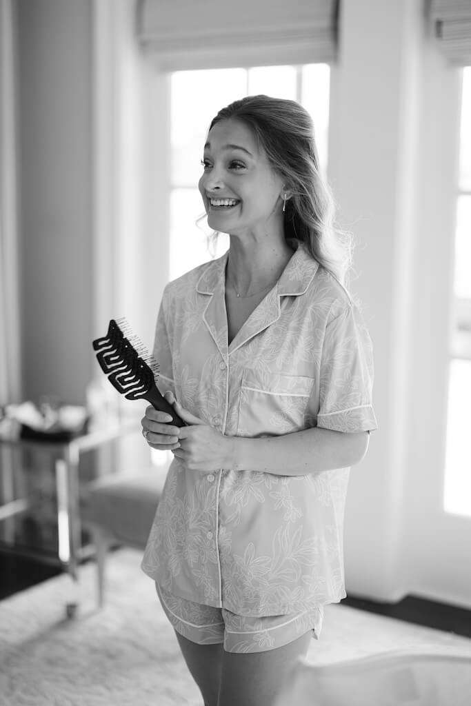 Candid shot of a bridesmaid adorning the bride in the bridal suite at Olivia and Landon's Oak Crossing Wedding in Lake Charles, LA, photographed by Morgan Alysse Photography.