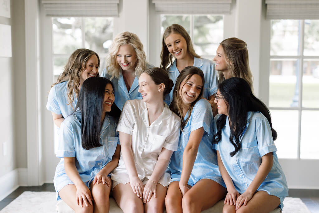 Bride  with her bridesmaids in their blue pjs in the bridal suite at Olivia and Landon's Oak Crossing Wedding in Lake Charles, LA, photographed by Morgan Alysse Photography.