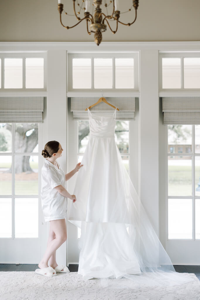 Bride  with her  her dress in the bridal suite at Olivia and Landon's Oak Crossing Wedding in Lake Charles, LA, photographed by Morgan Alysse Photography.