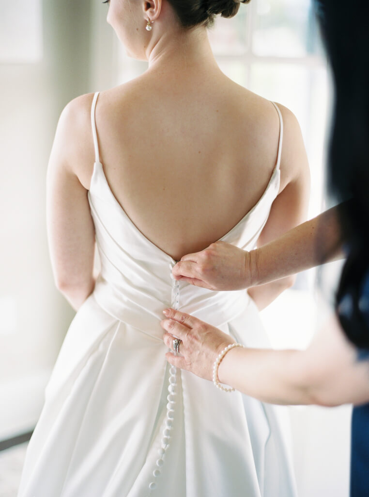 Bride  with her mom butting her dress in the bridal suite at Olivia and Landon's Oak Crossing Wedding in Lake Charles, LA, photographed by Morgan Alysse Photography.