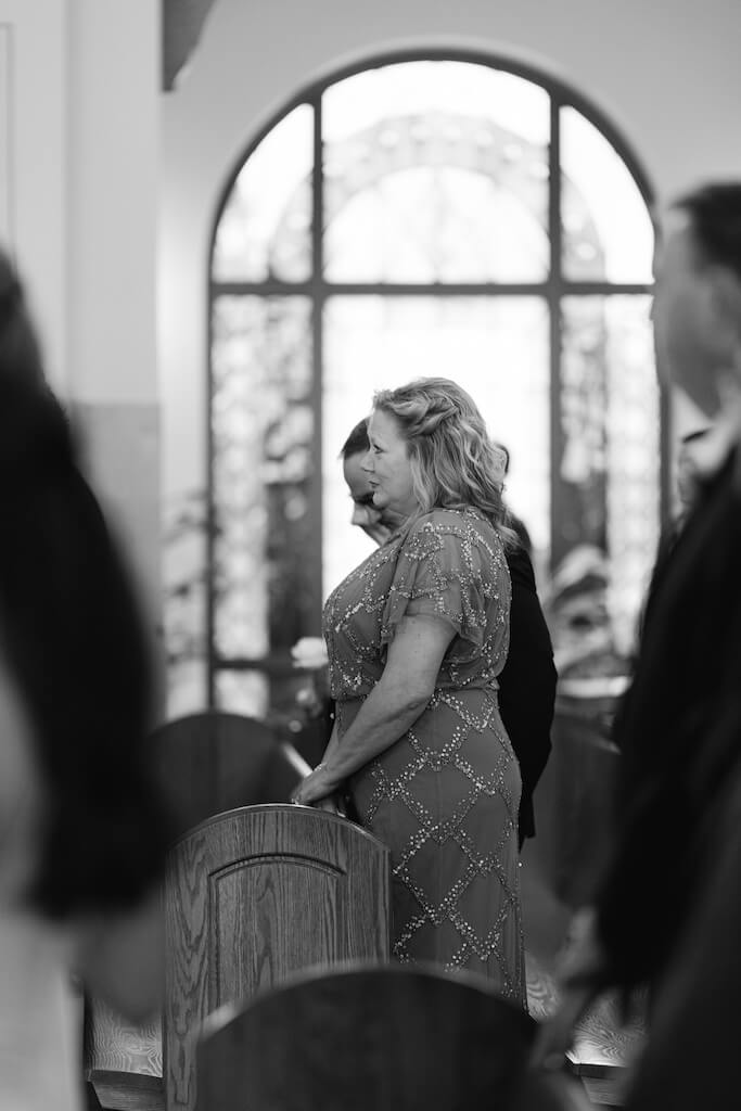 Grooms mom watching the bride walk down the aisle at St. Martin De Porres Catholic Church in Lake Charles, Louisiana, on Olivia and Landons Oak Crossing Wedding Day, photographed by Morgan Alysse Photography.