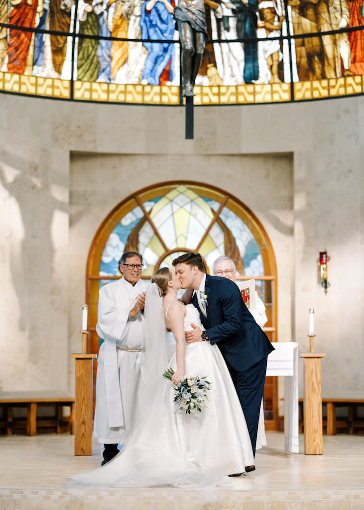 Bride and groom first kiss during their ceremony at St. Martin De Porres Catholic Church in Lake Charles, Louisiana, on Olivia and Landons Oak Crossing Wedding Day, photographed by Morgan Alysse Photography.