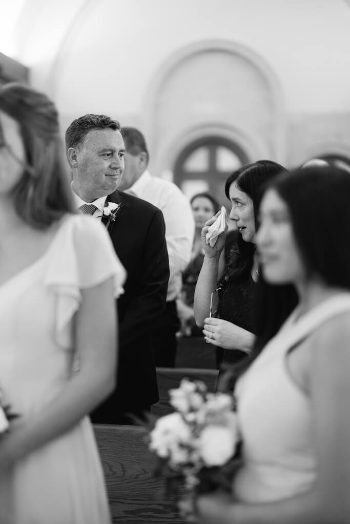 Brides mom and dad watching the bride walk down the aisle at St. Martin De Porres Catholic Church in Lake Charles, Louisiana, on Olivia and Landons Oak Crossing Wedding Day, photographed by Morgan Alysse Photography.