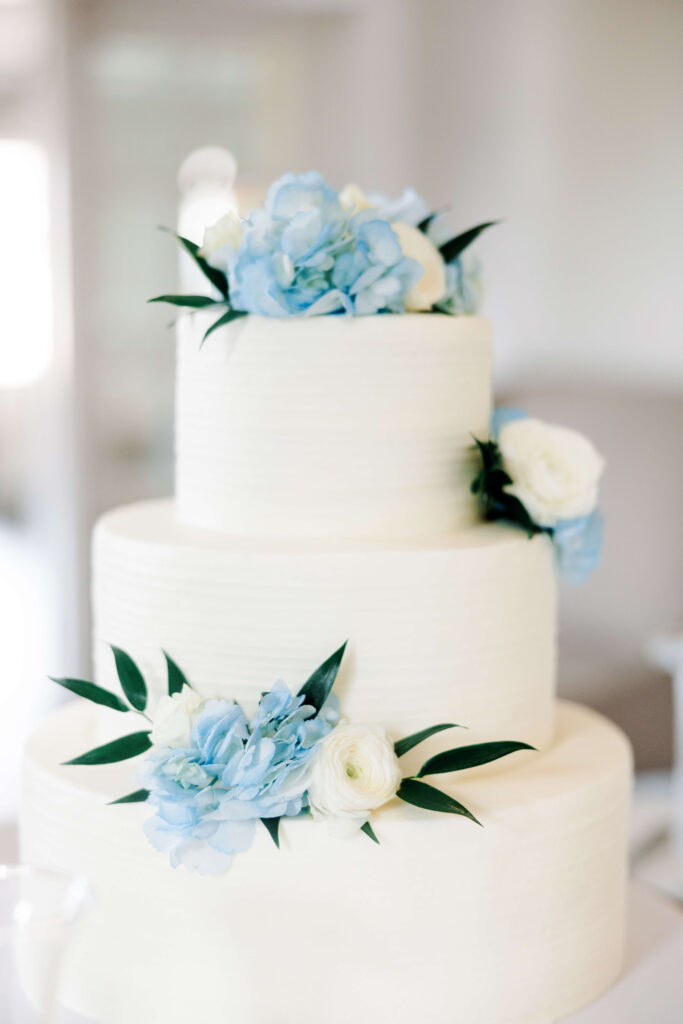 Wedding Cake with blue flowers at Olivia and Landon's Oak Crossing Wedding in Lake Charles, LA, photographed by Morgan Alysse Photography.