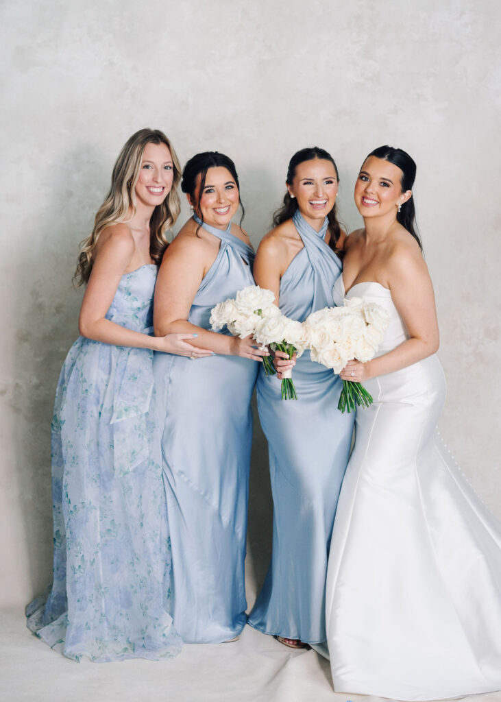 Bride and bridesmaids dressed in dusty blue before Lauren and Colby's rainy day wedding at The Madison in Broussard, LA, photographed by Morgan Alysse Photography.