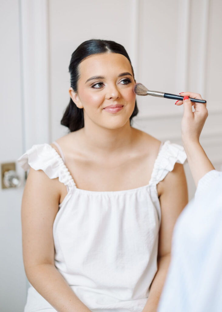 Bride getting makeup done before Lauren and Colby's rainy day wedding at The Madison in Broussard, LA, photographed by Morgan Alysse Photography.