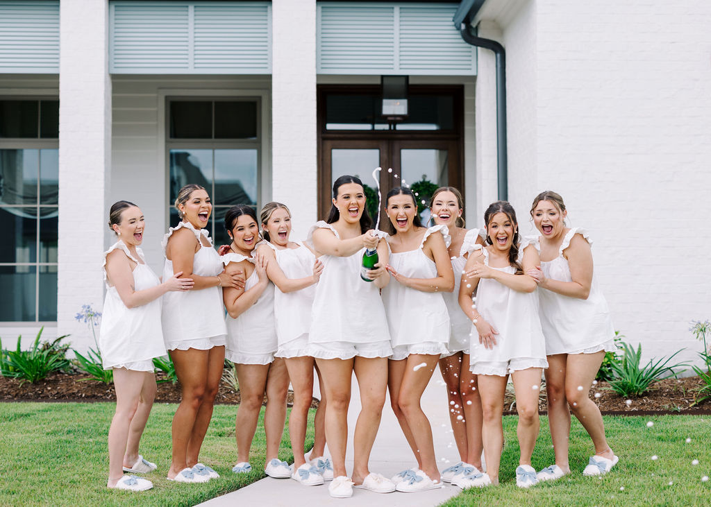 Bride and bridesmaids popping champagne before Lauren and Colby's rainy day wedding at The Madison in Broussard, LA, photographed by Morgan Alysse Photography.