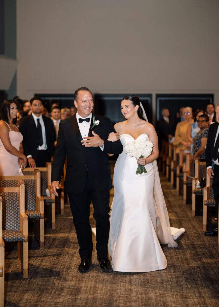 Bride walking down the aisle with father at Lauren and Colby's rainy day wedding ceremony at Our Savior's Church in Lafayette, LA, photographed by Morgan Alysse Photography.