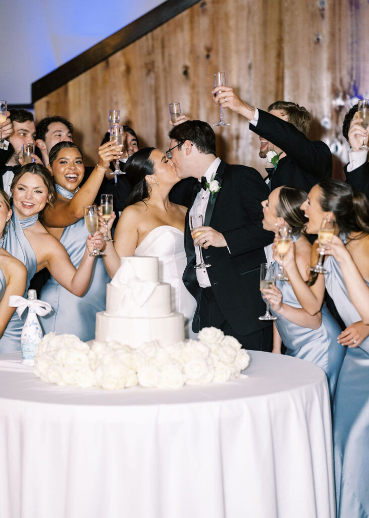 Bride and groom kissing by the cake at Lauren and Colby's rainy day wedding at The Madison in Broussard, LA, photographed by Morgan Alysse Photography.