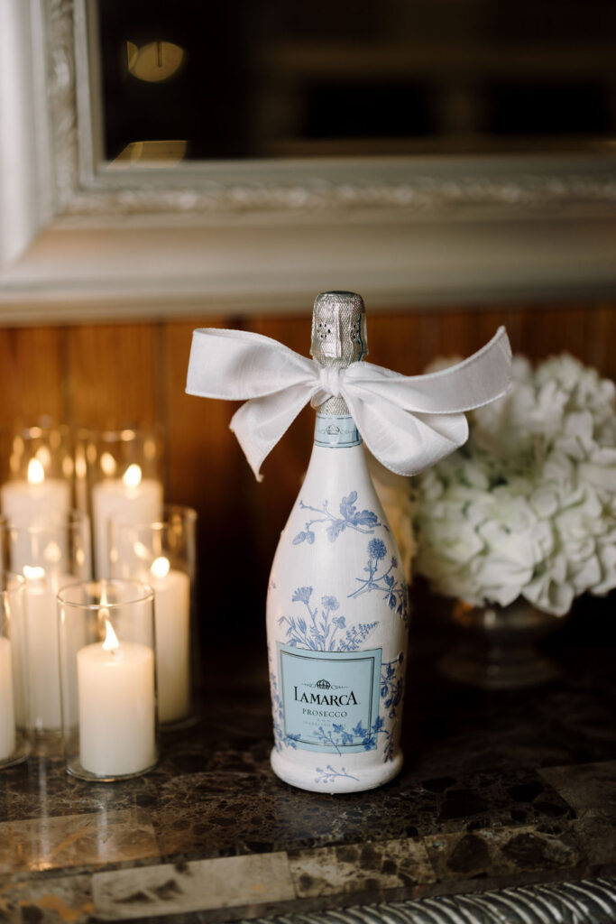 A champagne bottle with a bow at Lauren and Colby's rainy day wedding at The Madison in Broussard, LA, photographed by Morgan Alysse Photography.