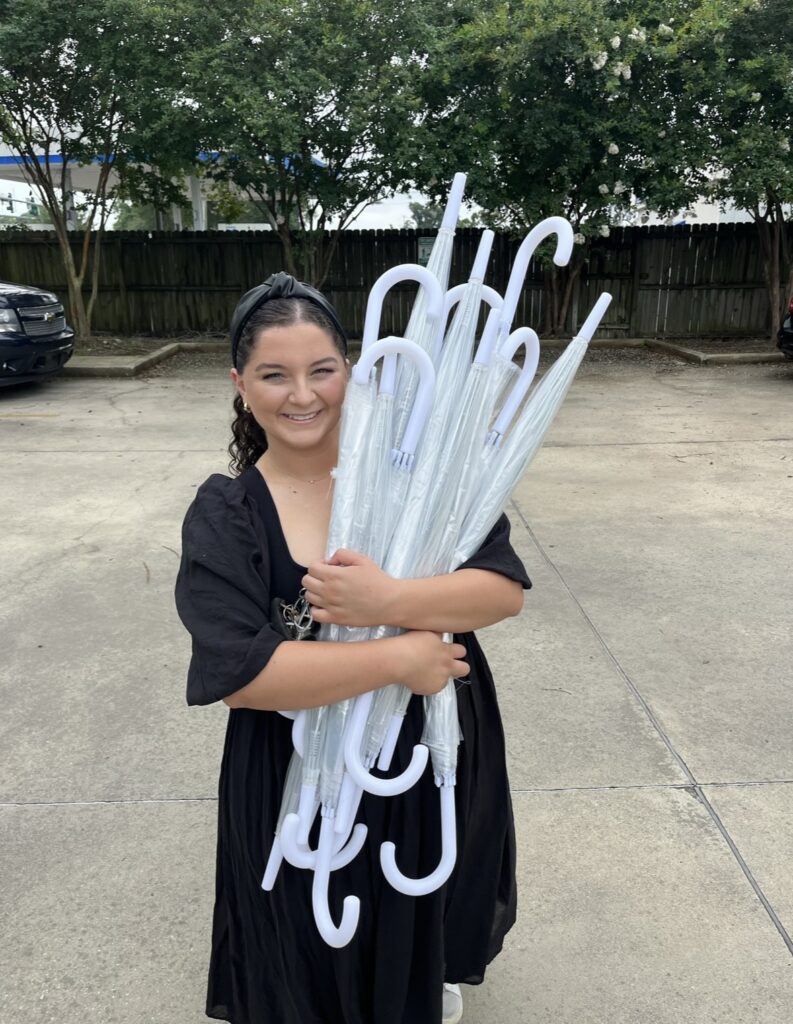 Morgan holding umbrellas at Lauren and Colby's rainy day wedding at The Madison in Broussard, LA.