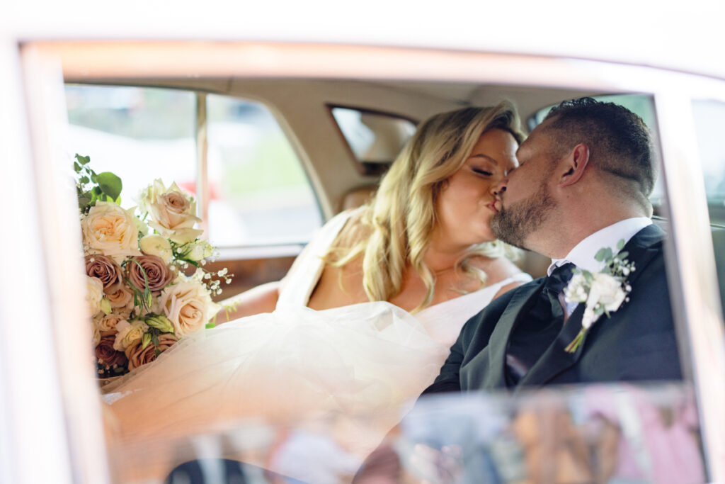 Bride and groom kissing in a Rolls Royce limo at their wedding captured by Morgan Alysse Photography