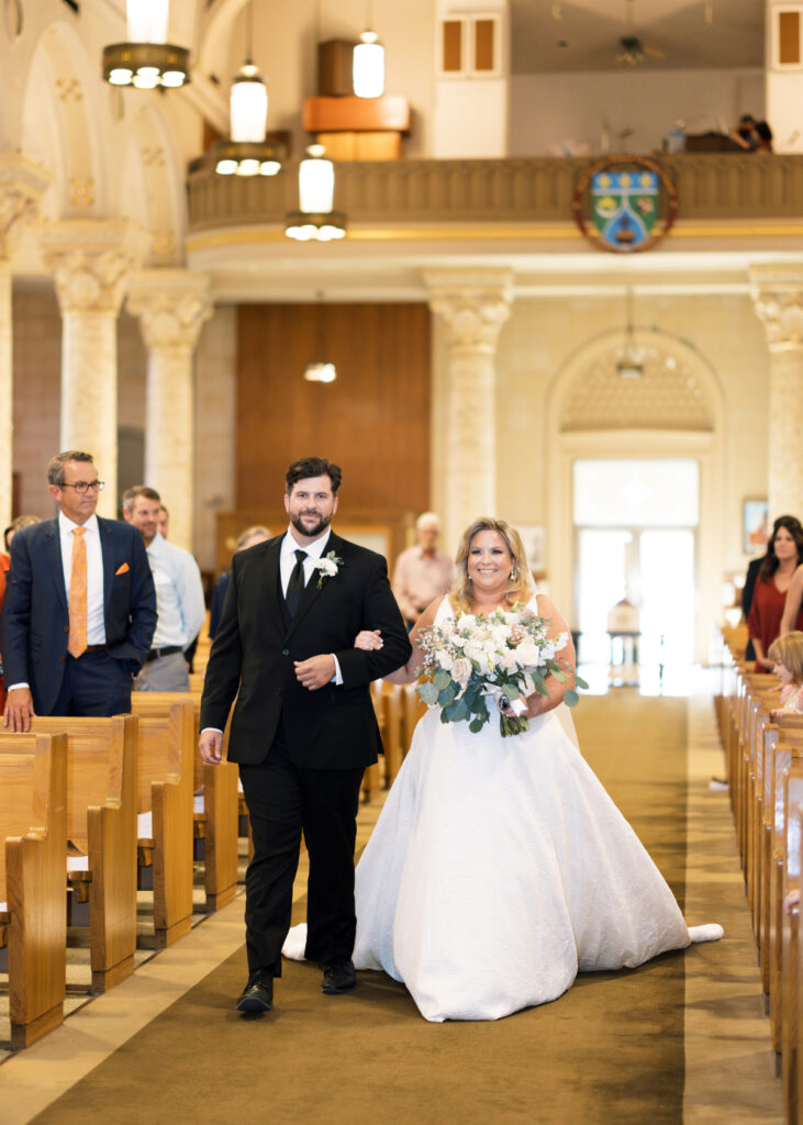 Bride walks down the aisle with her brother at her wedding at St Landry Catholic Church captured by Morgan Alysse Photography