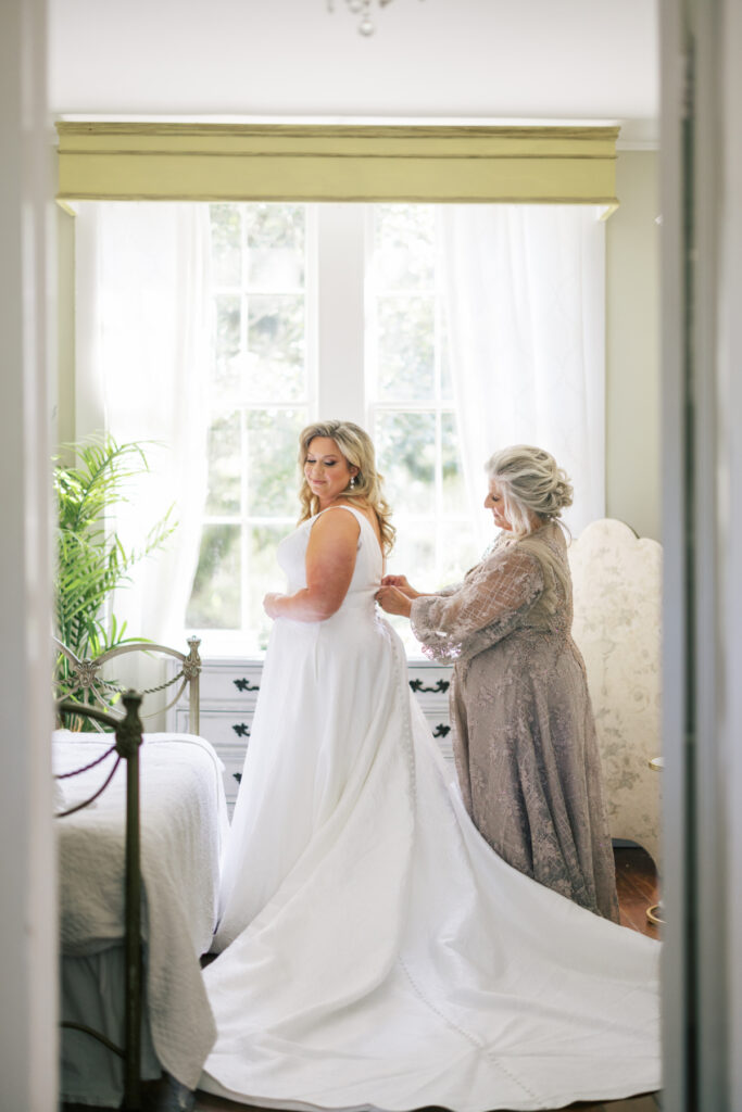 Bride getting dressed with her mother before her Opelousas wedding captured by Morgan Alysse Photography