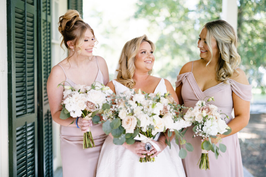 Bride and two bridesmaids dressed in blush pink holding bouquets