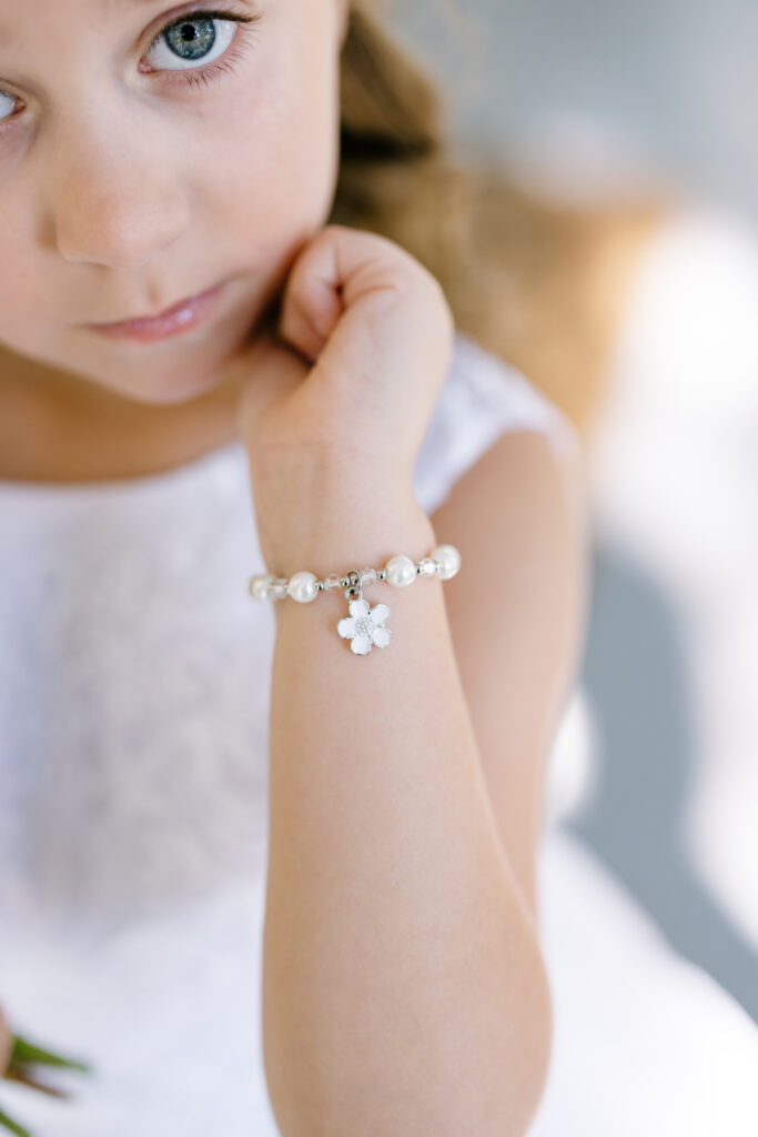 Flower girl posing with a special bracelet before an Opelousas wedding captured by Morgan Alysse Photography