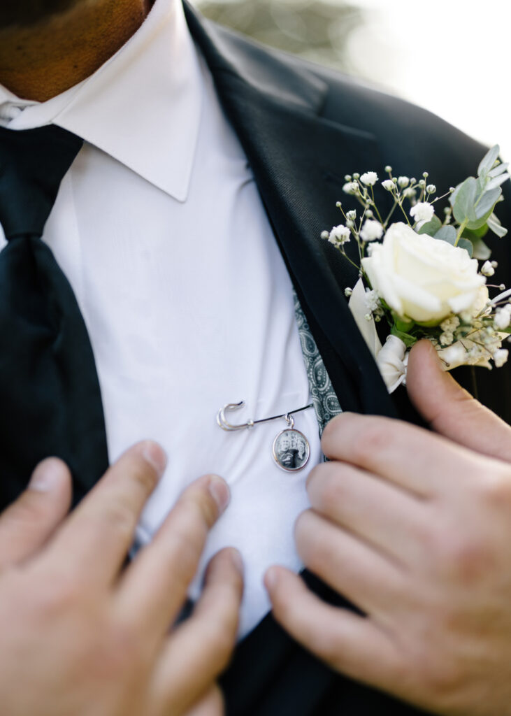 Groom's boutonniere and special pin under his tuxedo