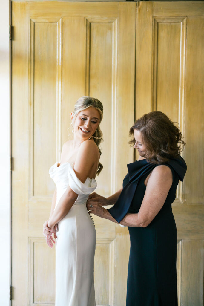 Sean’s mother helping Brie button her wedding dress before the ceremony