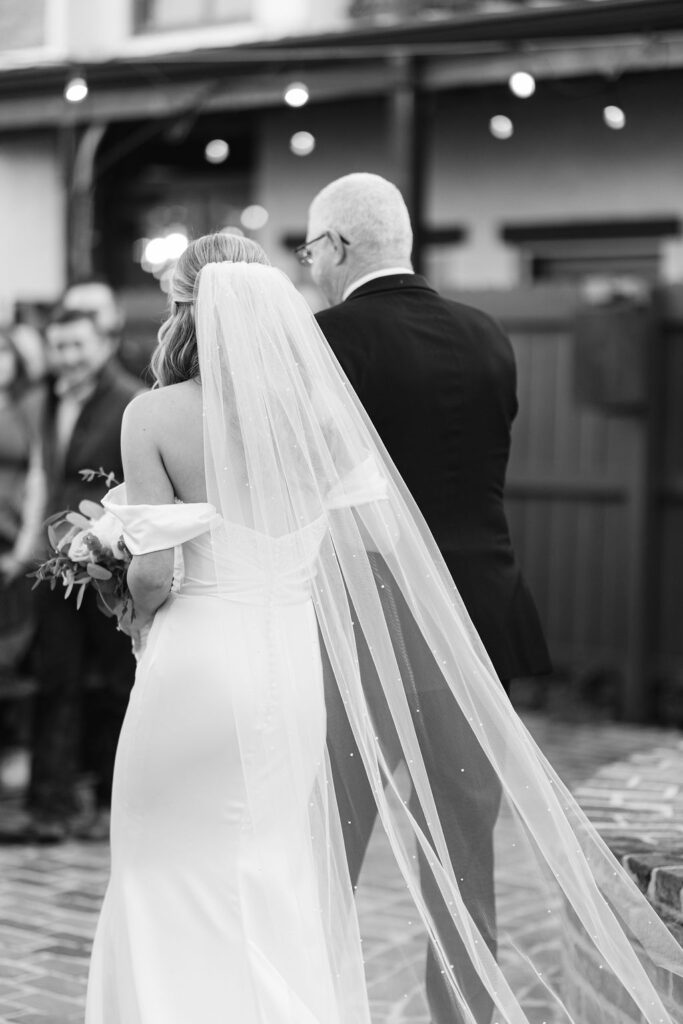 The bride walking down the aisle in the courtyard at Maison de Tours