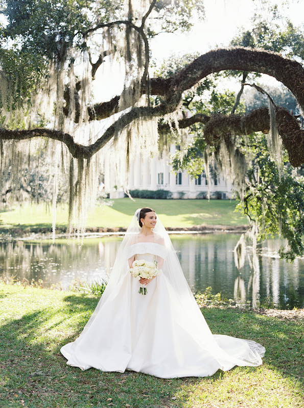 Sunlight filtering through oak trees, highlighting a bride’s classic wedding gown.