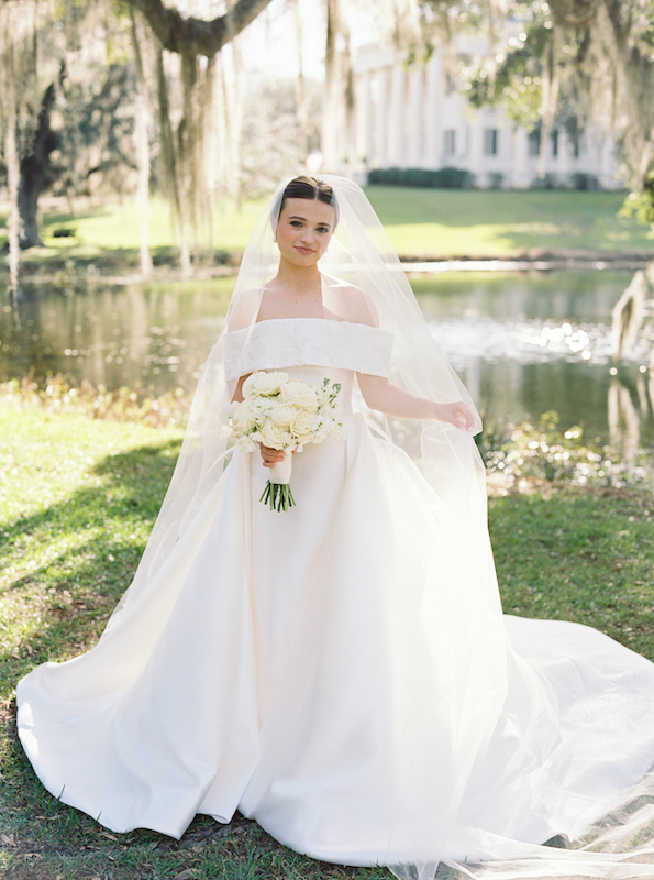 A Southern bride smiling beneath Spanish moss in a timeless wedding dress.