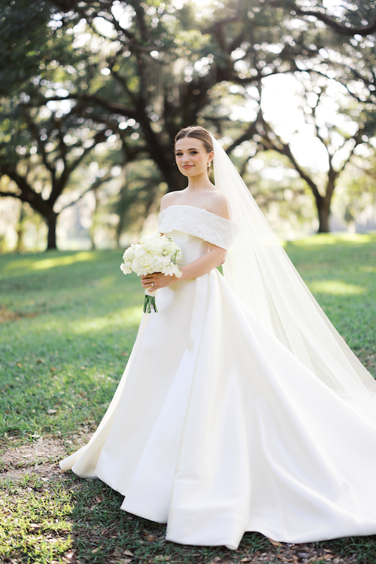 Bride standing gracefully on the grand front porch of a Southern estate.